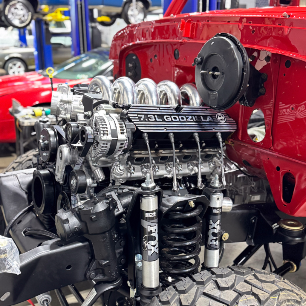 Detailed view of the 7.3L Godzilla engine and suspension system in a 1978 Ford Bronco, featuring FOX shocks and BDS components during a restomod build at NFI Empire's shop