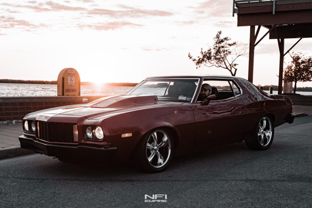 Restored red 1976 Ford Torino restomod in front of the setting sun