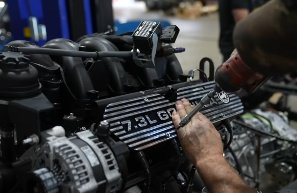 Close-up of a 7.3L Godzilla engine being worked on in a garage, showcasing the meticulous craftsmanship behind restomod builds at NFI Empire.